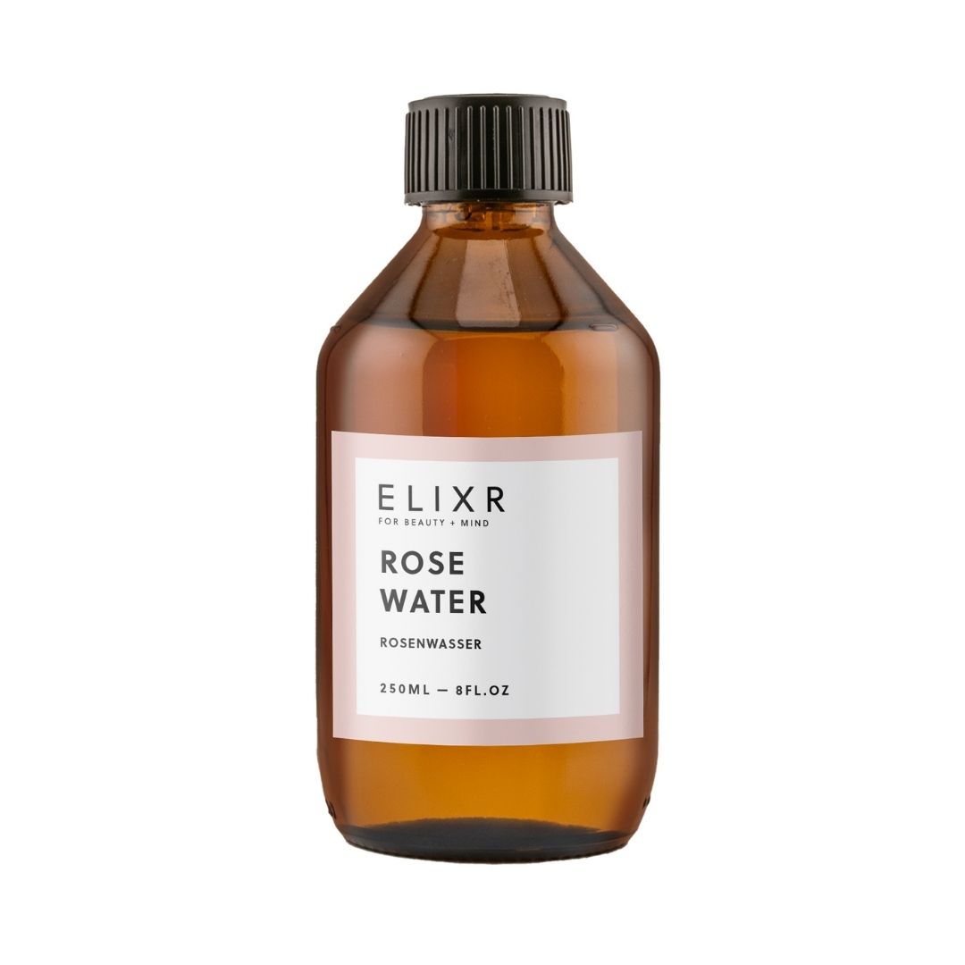 Braune Glasflasche mit schwarzem Deckel. Etikett mit Text: ELIXR, Rose Water, Rosenwasser. Volumenangabe.