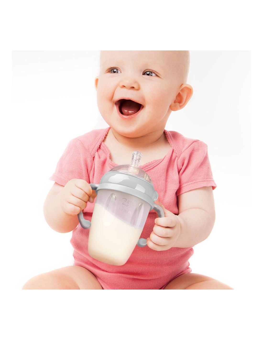 Baby hält eine Flasche mit Griffen. Die Flasche enthält Flüssigkeit. Das Baby lächelt.