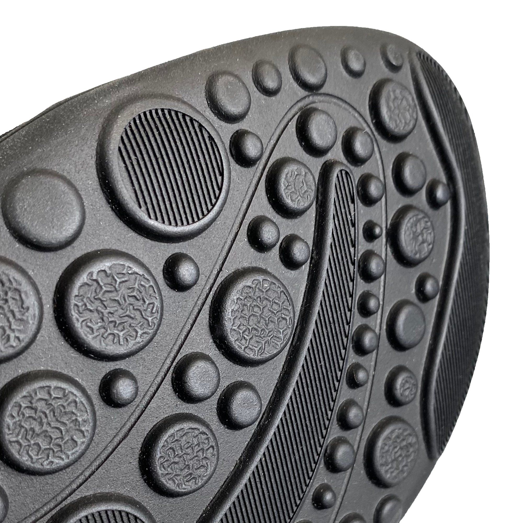 Detailansicht der schwarzen Sohle einer Stiefelette. Profil mit Kreisen und Rillen.