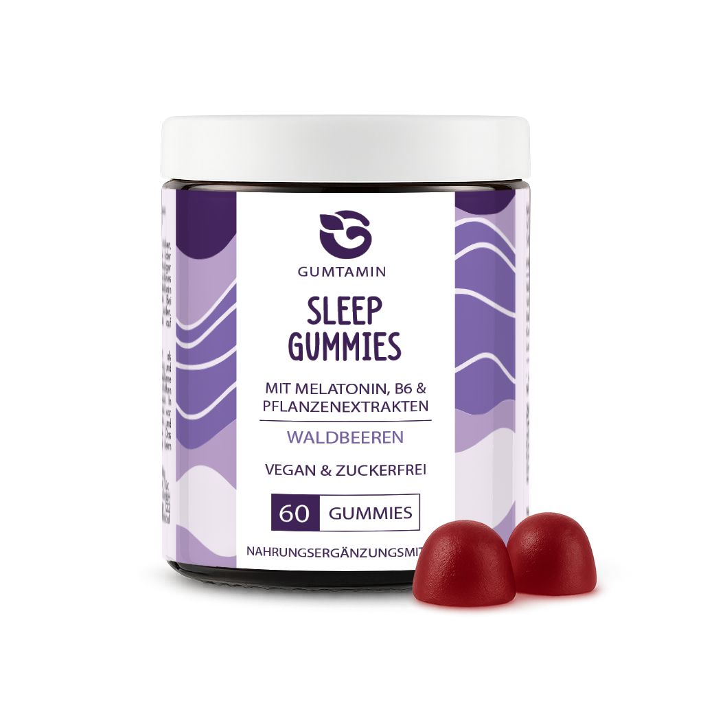 Weißes Glas mit lila Etikett. Aufschrift: Gumtamin Sleep Gummies, 60 Gummies, Waldbeeren. Zwei rote Gummibärchen daneben.