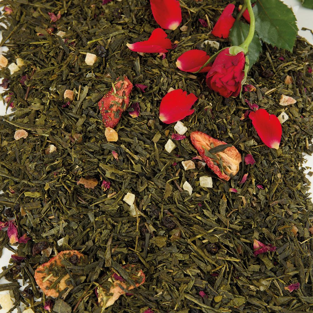 Grüner Tee mit roten Rosenblättern und Fruchtstücken. Nahaufnahme.