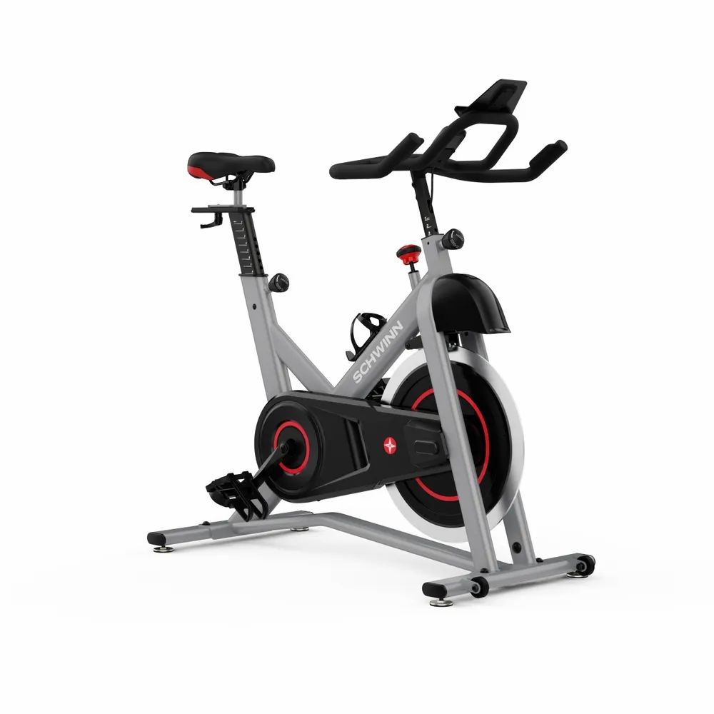 Grauer Heimtrainer mit rotem Akzent. Schwarzes Schwungrad, Lenker, Sattel und Pedale. Marke: Schwinn.