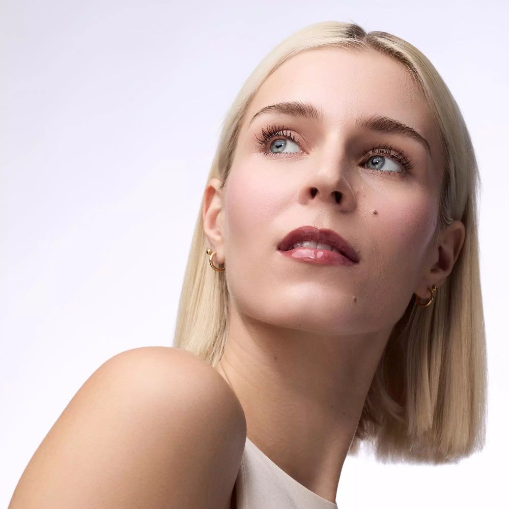 Porträt einer blonden Frau, die nach oben blickt. Sie trägt Lippenbalsam.