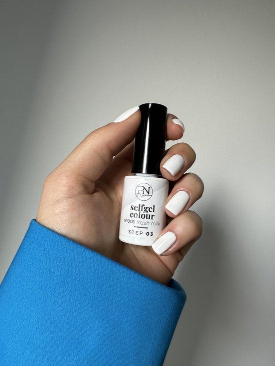 Hand mit weiß lackierten Nägeln, hält eine Flasche Nagellack. Auf der Flasche steht "PN selfgel colour N001 fresh milk STEP 03".