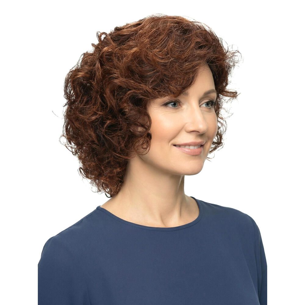 Frau mit brauner, lockiger Perücke. Nahaufnahme, seitliche Ansicht. Die Perücke bedeckt den Kopf und hat kurze Locken. Die Frau lächelt.