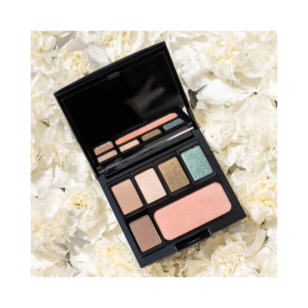 Geöffnete schwarze Beauty Box mit verschiedenen Lidschatten und Rouge, auf weißen Blüten.