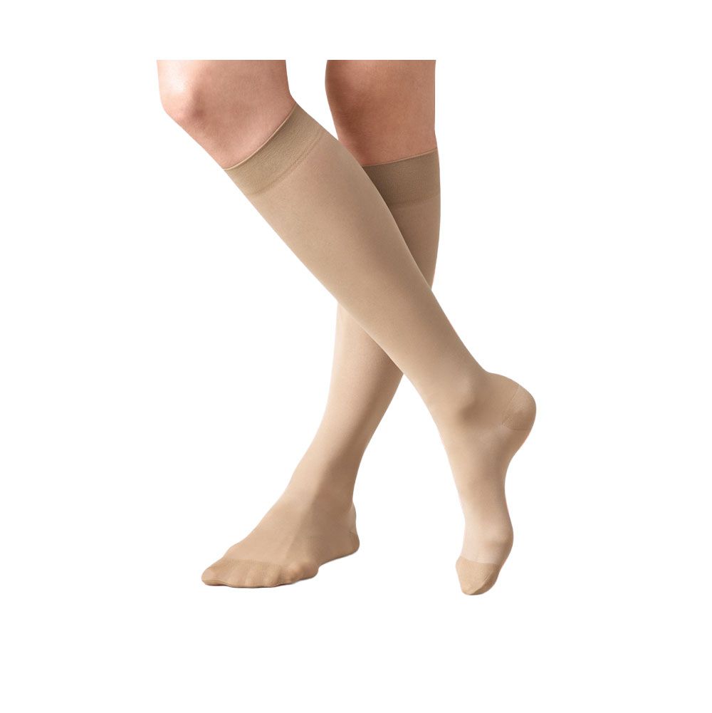 Hautfarbene Kniestrümpfe. Feines Material, leicht transparent. Beige Abschlussbündchen. Auf Beinen getragen.