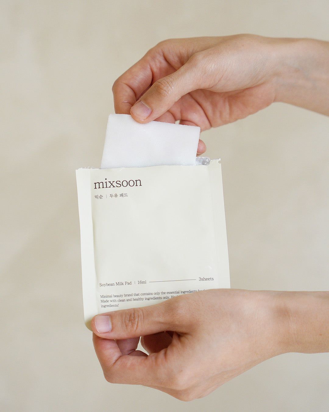 Hände halten eine geöffnete Einzelverpackung mit einem Pad. Aufschrift: mixsoon, Soybean Milk Pad.