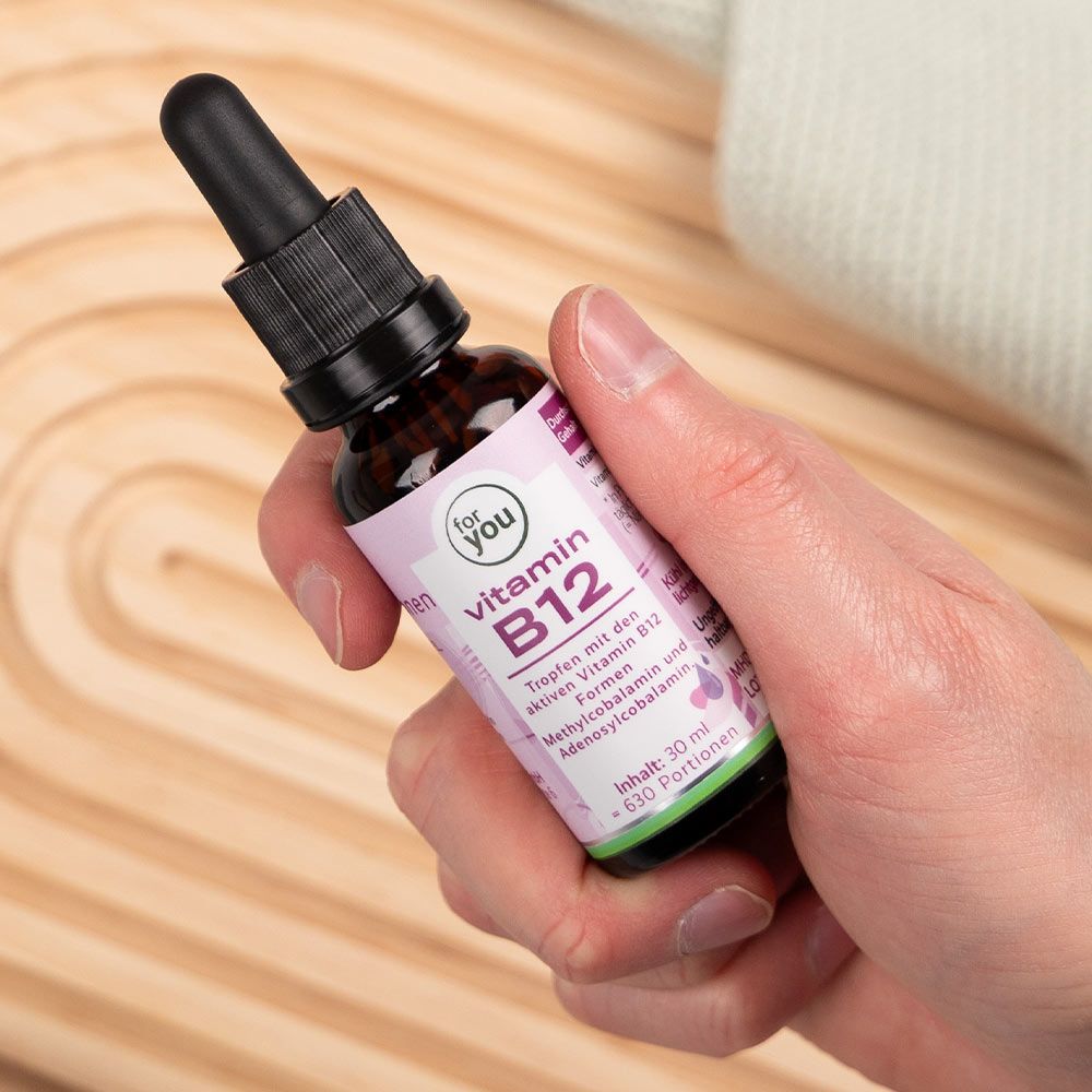 Hand hält Flasche mit Pipette. Etikett mit "for You" und "Vitamin B12".