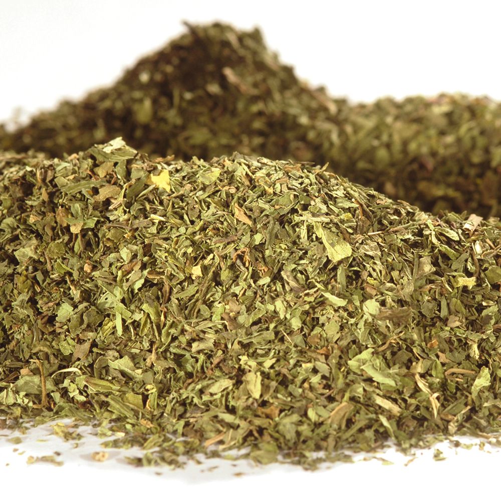 Haufen loser Spearmint/Krauseminze Tee. Grüne Blätter, leicht unscharf, vor weißem Hintergrund.
