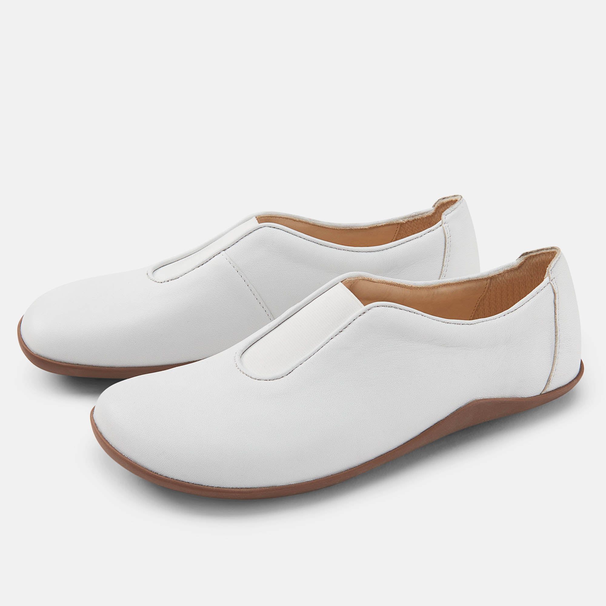 Weiße Slipper mit brauner Sohle. Zwei Schuhe nebeneinander, Ansicht von der Seite.