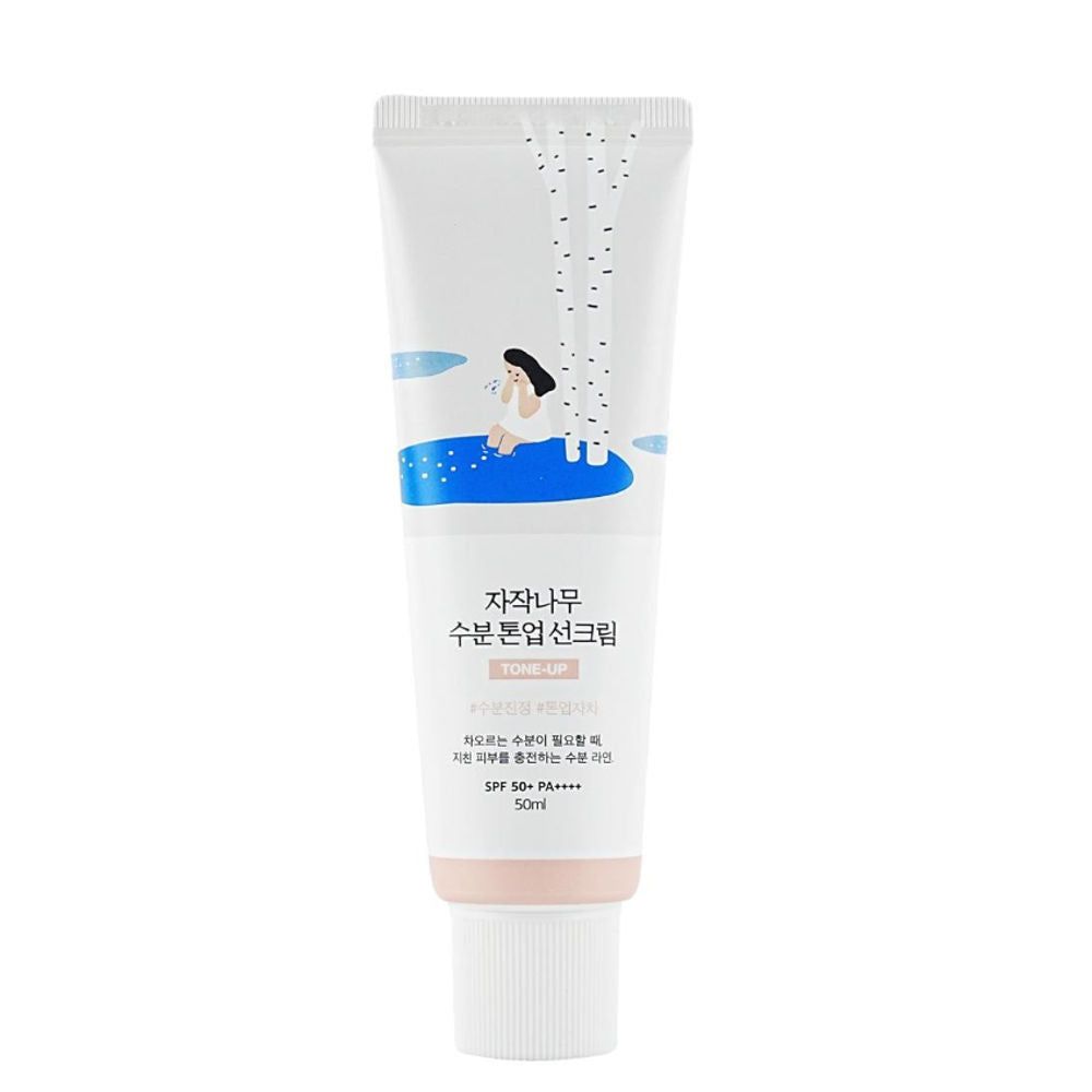 Weiße Tube mit koreanischem Text und Illustration. Rosafarbener Boden. SPF 50+ PA++++.