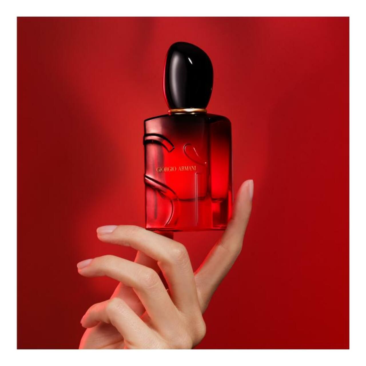 Roter Flakon, gehalten von einer Hand. Schwarzer Verschluss. Aufschrift: Giorgio Armani.