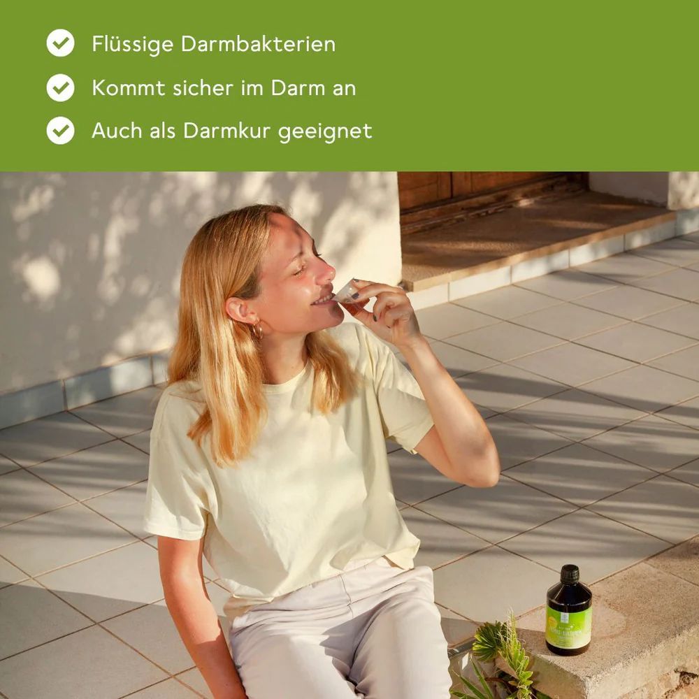 Frau trinkt aus einem Messbecher. Aufschrift: BitterLiebe Probio Kulturen Komplex. Hintergrund: Terrasse.