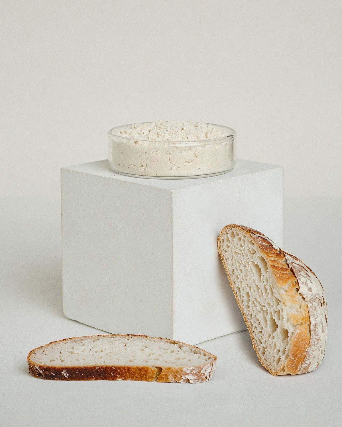 Guarkernmehl Pulver in einer Schale auf einem Würfel, daneben Brotscheiben.