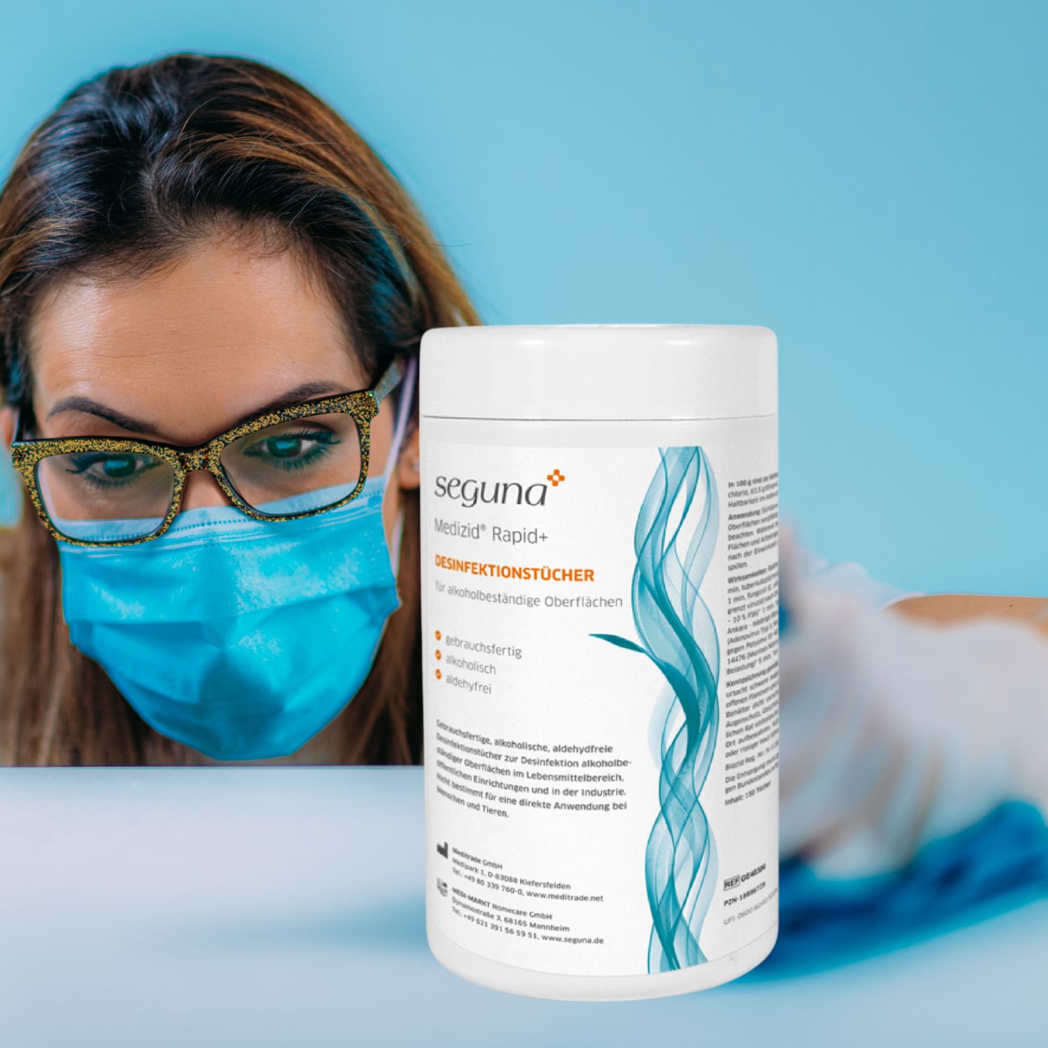 Person mit Brille und Maske, Dose SEGUNA Medizid Rapid+ Desinfektionstücher. Person wischt Oberfläche. Dose mit Etikett.