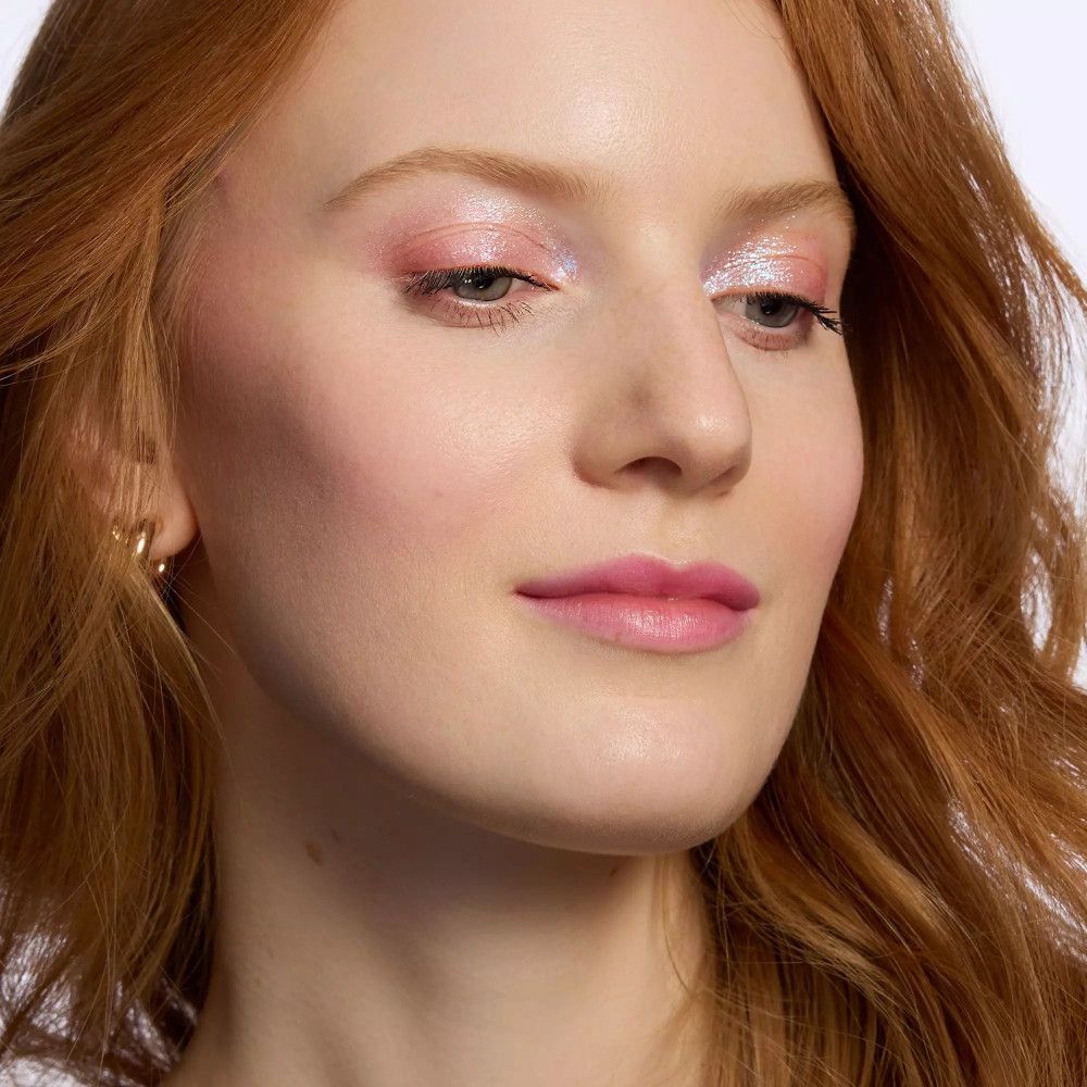 Eine Frau mit rosa Lidschatten und Lippenstift. Der Lidschatten ist glänzend und schimmert.