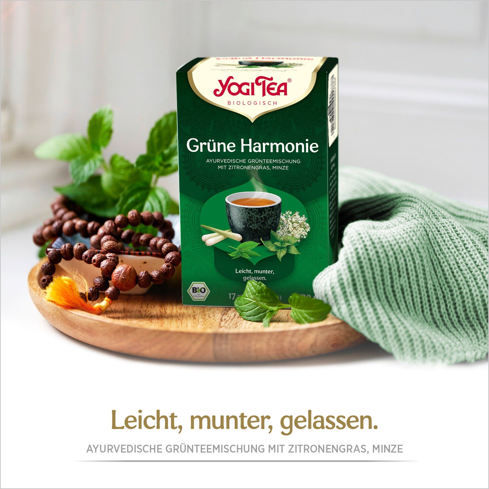 Grüne Schachtel Yogi Tea - Grüne Harmonie Bio Grüntee. Aufdruck: 17 Teebeutel, Bio-Siegel. Daneben Kräuter und Schmuck.