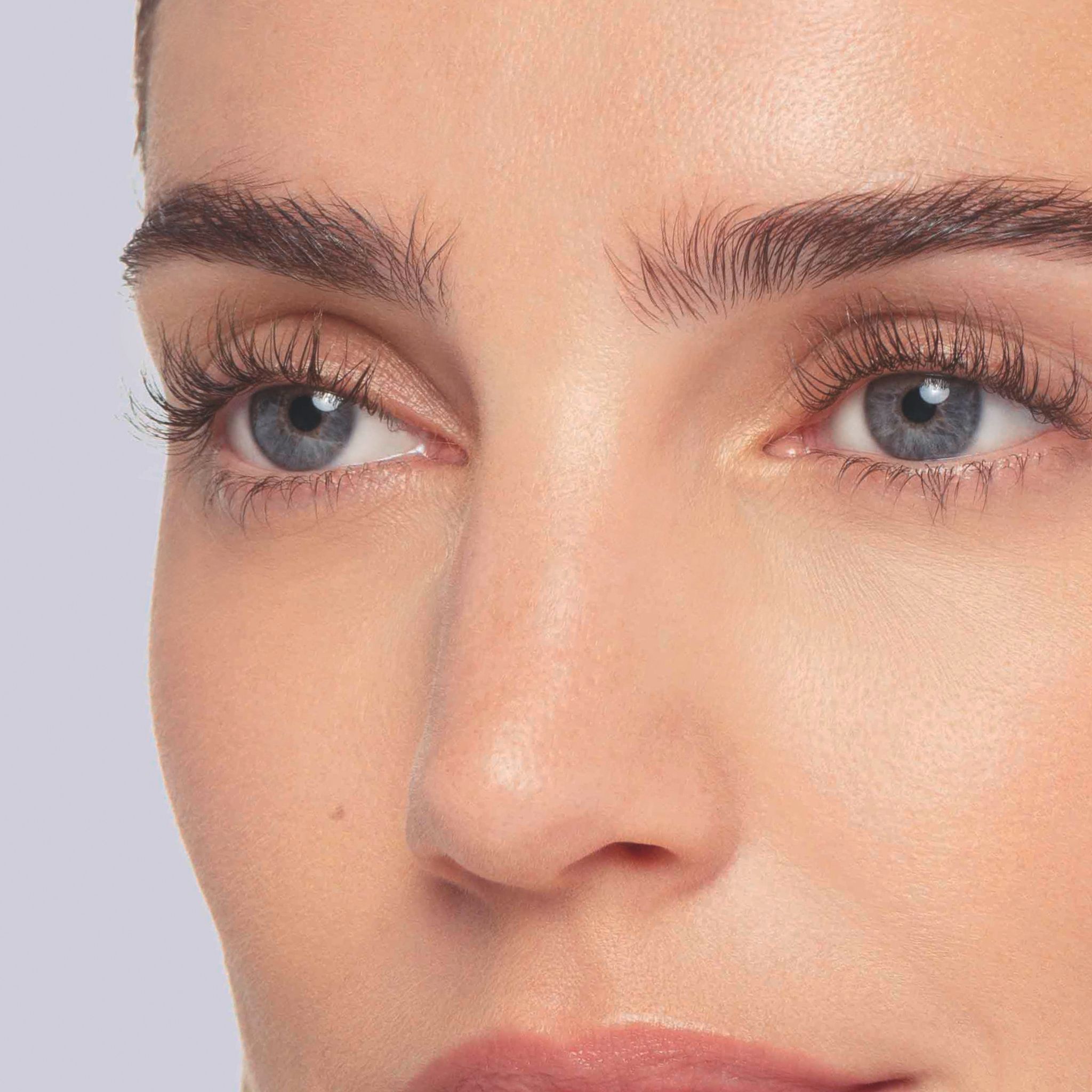 Nahaufnahme der blauen Augen einer Frau mit perfekt geschwungenen Wimpern.