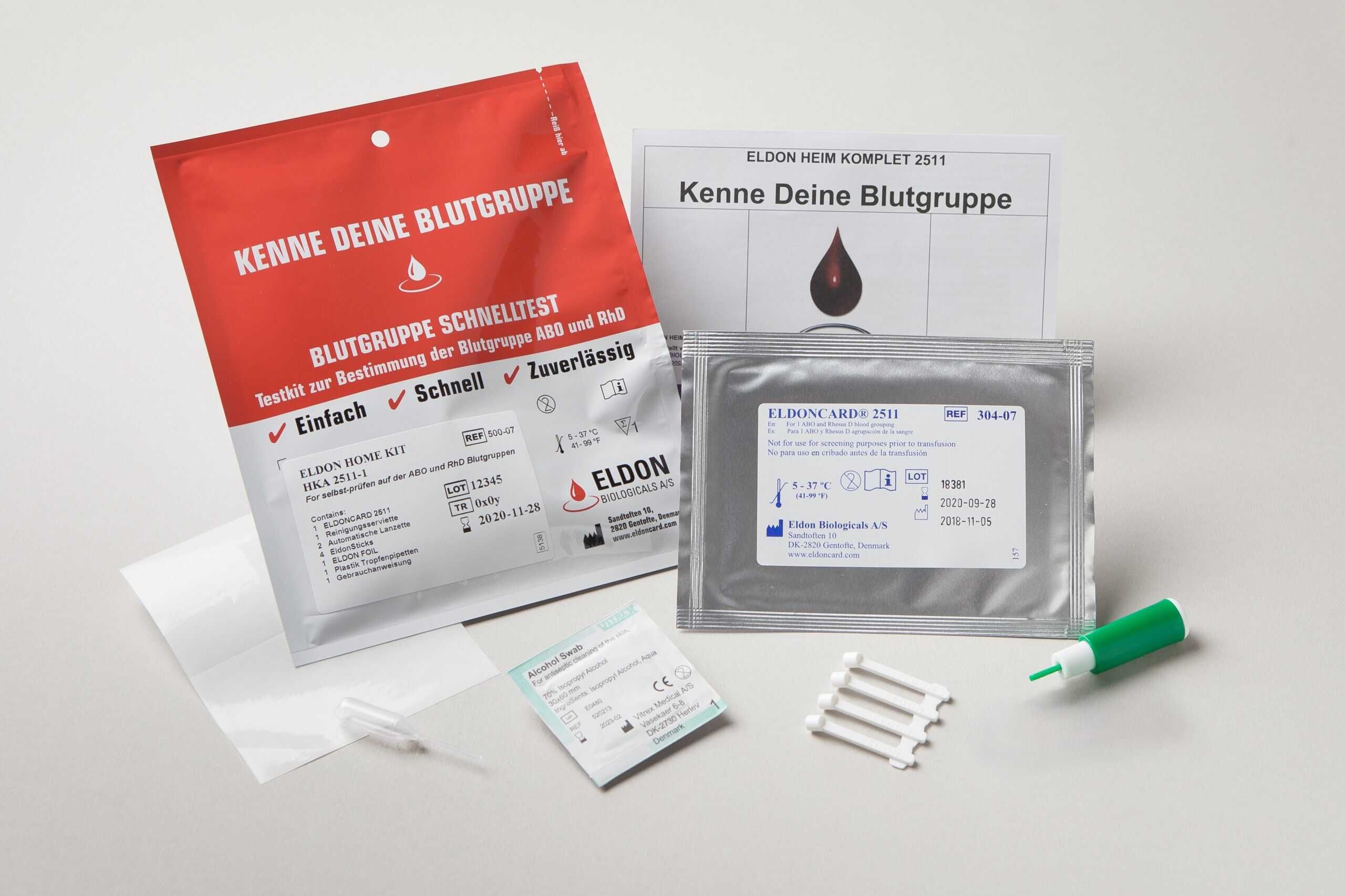 Blutgruppentest-Kit. Rote und silberne Verpackungen, Testkarten, Lanzette, Anweisungen. Text: Eldon, Blutgruppe, Schnelltest.