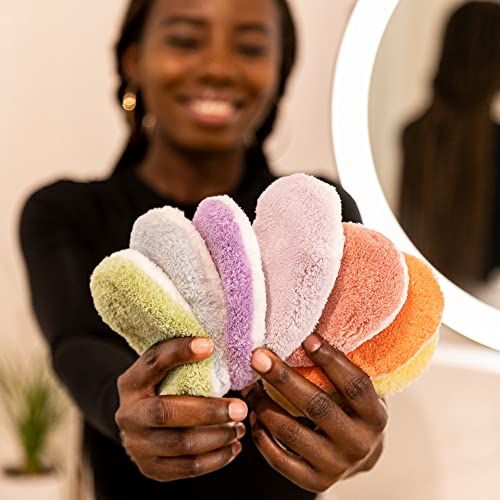 Hände halten eine Reihe von Abschminkpads in verschiedenen Farben. Pads sind oval und weich. Person lächelt.