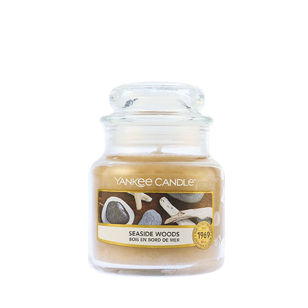 Duftkerze im Glas mit Deckel. Aufschrift: Yankee Candle, Seaside Woods, Bois en bord de mer. Abbildung von Steinen und Treibholz.