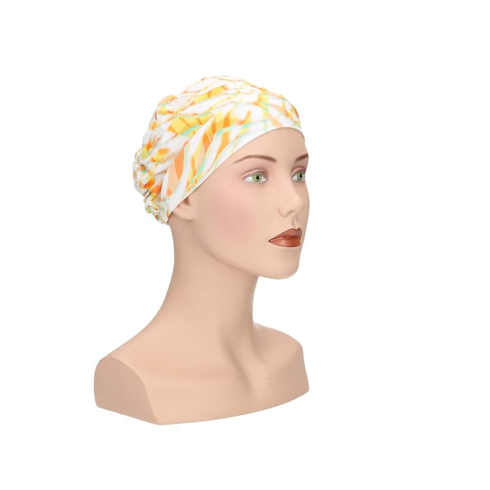 Turban mit gelb-orangem Muster auf einem Schaufensterpuppenkopf. Seitenansicht.