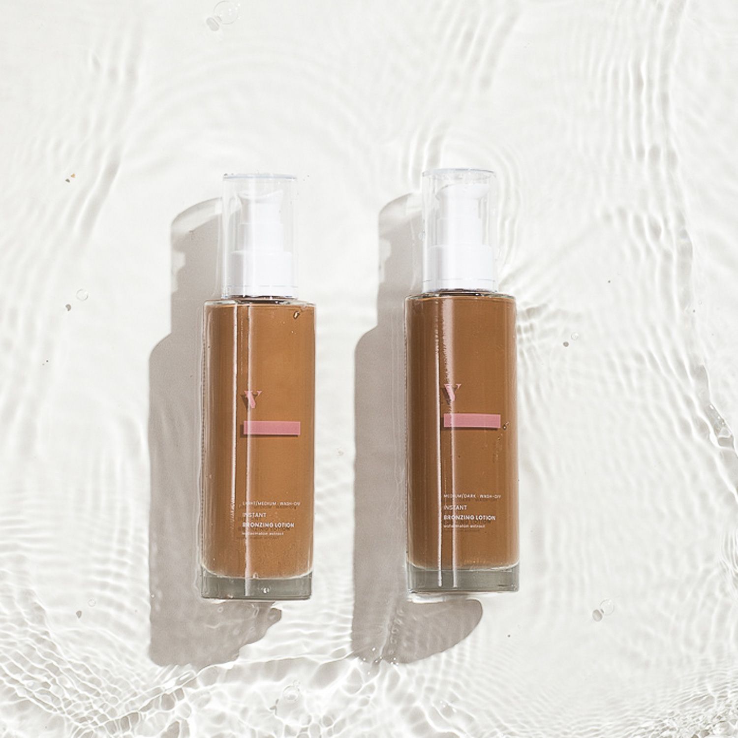 Zwei braune Lotionflaschen mit weißen Pumpköpfen im Wasser. Aufschrift: Instant Bronzing Lotion.