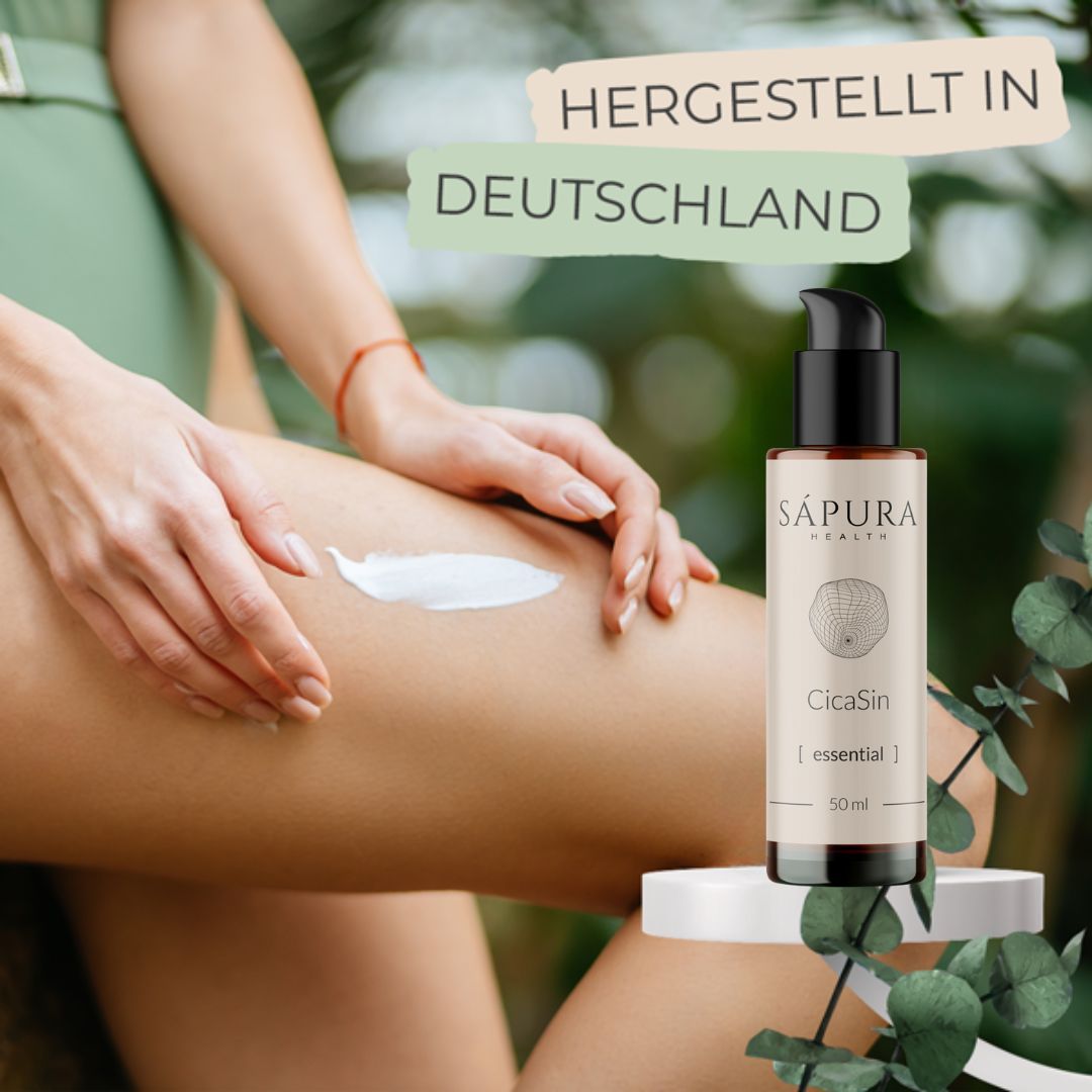 Bein mit aufgetragener Creme. Flasche daneben. Aufschrift: Sápura Health, CicaSin [essential], 50 ml. Text: HERGESTELLT IN DEUTSCHLAND.