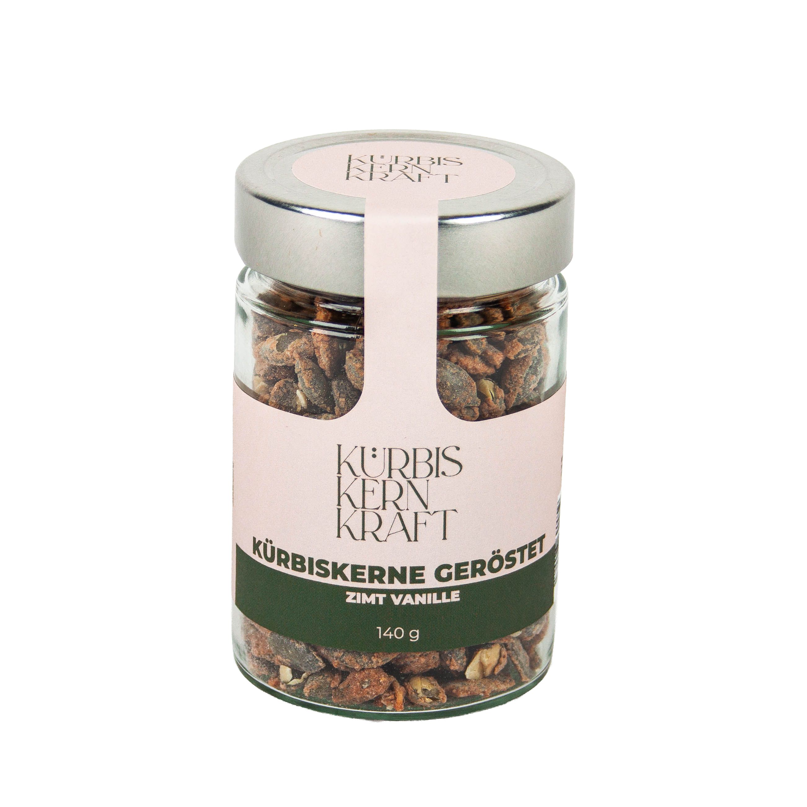 Glas mit gerösteten Kürbiskernen. Etikett mit "Kürbis Kern Kraft", "Zimt Vanille" und "140 g". Deckel silberfarben.