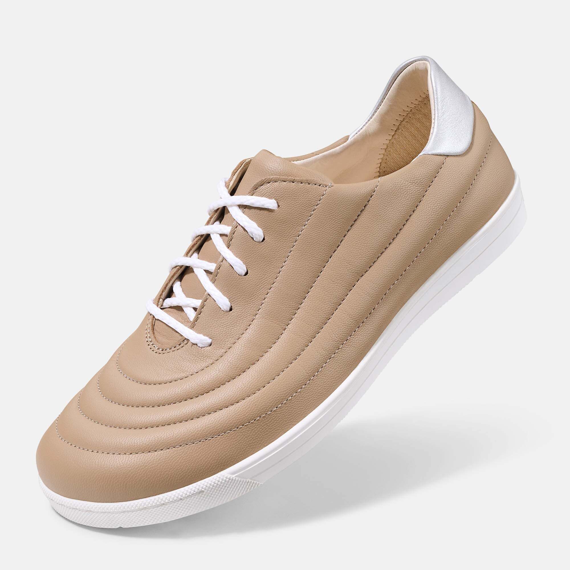 Ein beiger Damen-Schnürschuh aus Leder mit weißer Sohle, von der Seite betrachtet.