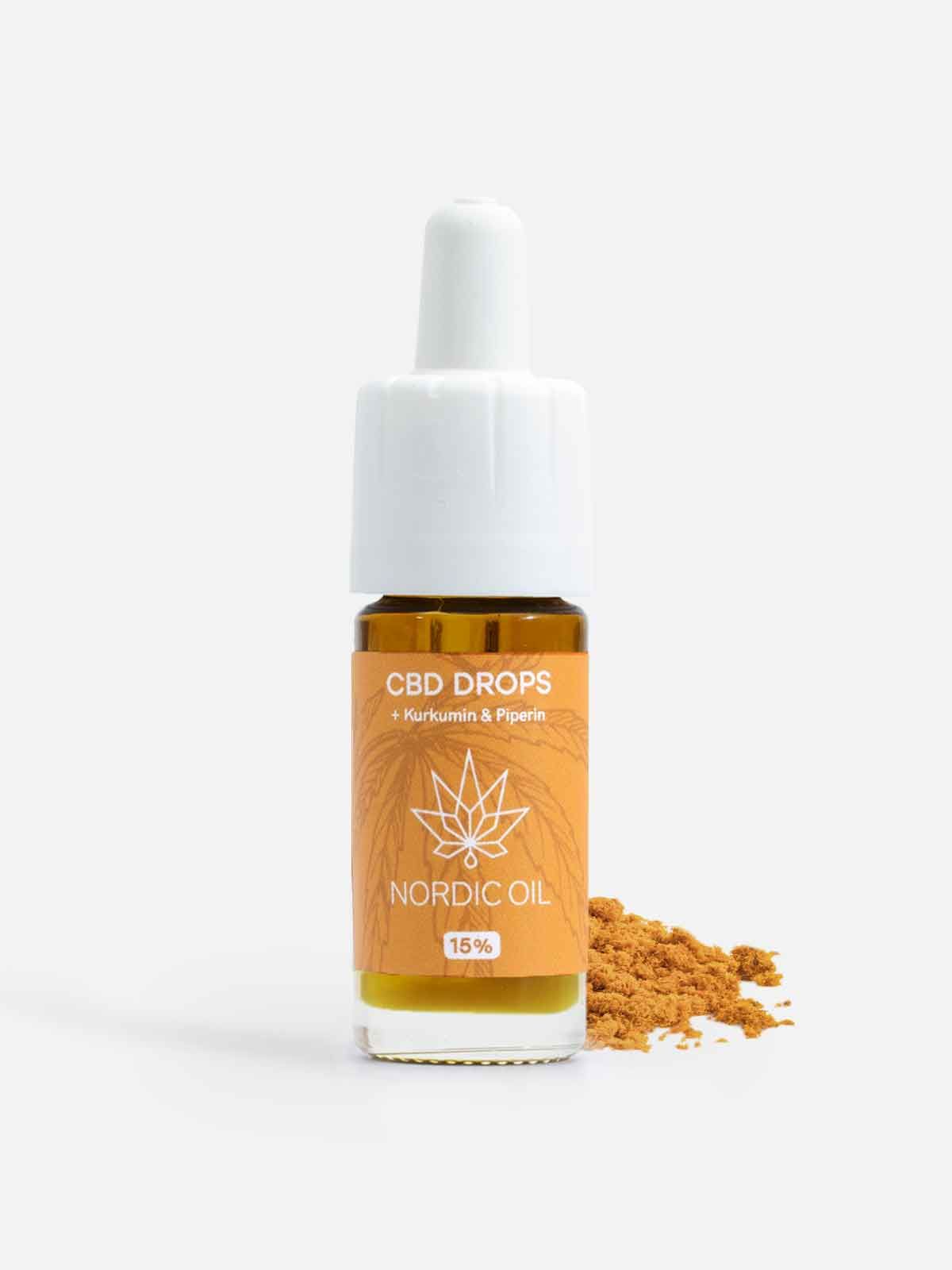 Braunglasflasche mit weißem Verschluss. Etikett mit Text: CBD DROPS, Nordic Oil, 15%. Kurkumin und Piperin. Braunes Pulver daneben.