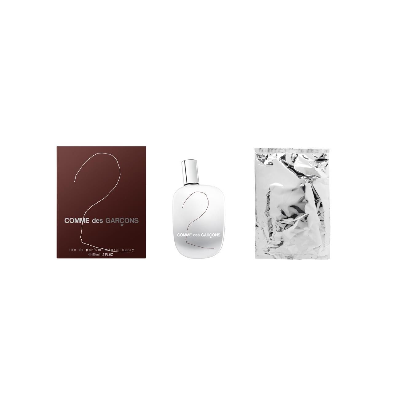 Parfümflakon und Verpackung. Flakon und Verpackung mit der Aufschrift "2 Comme des Garcons". Silberfarbener Beutel.