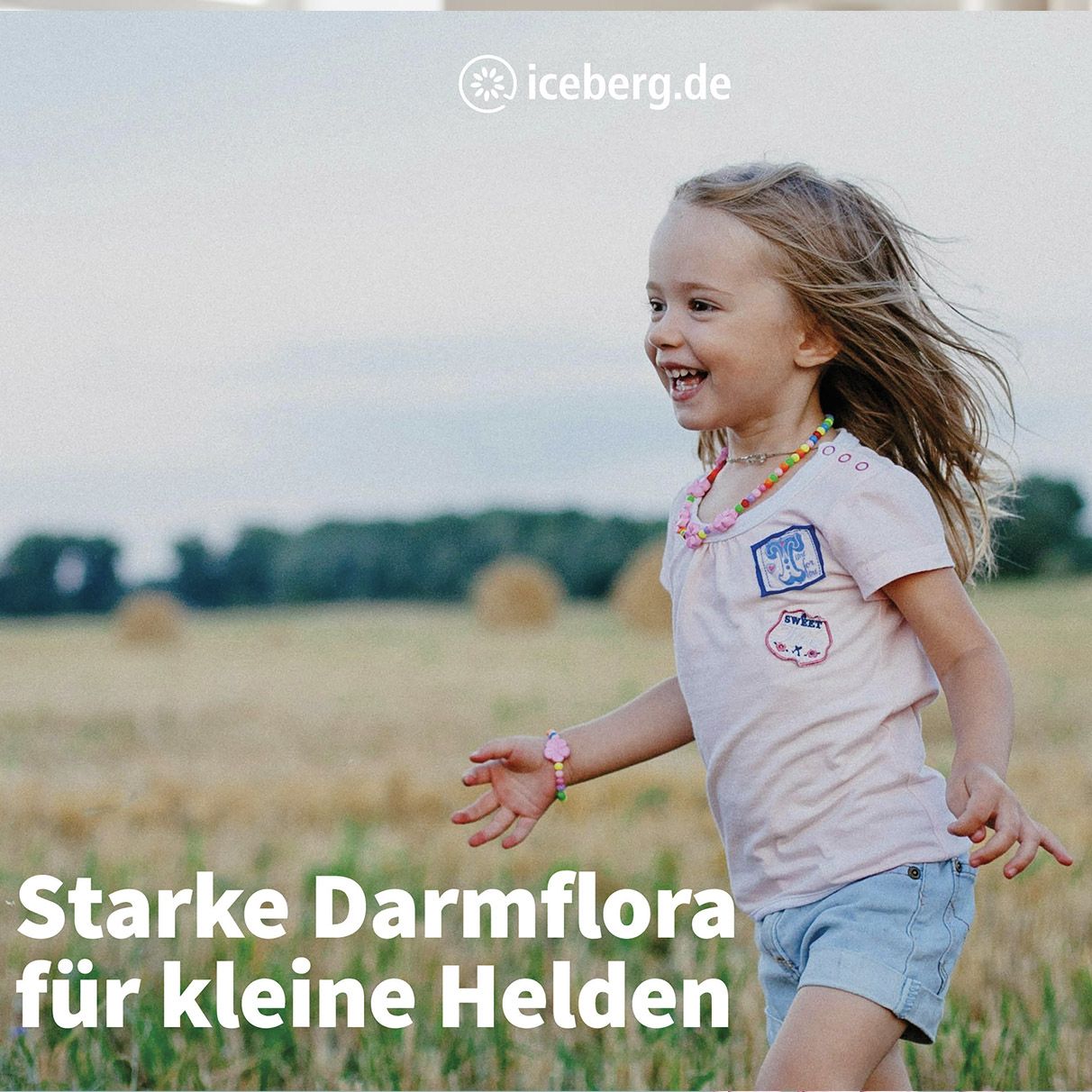 Kind lacht auf Feld. Text: Starke Darmflora für kleine Helden. Logo: iceberg.de.