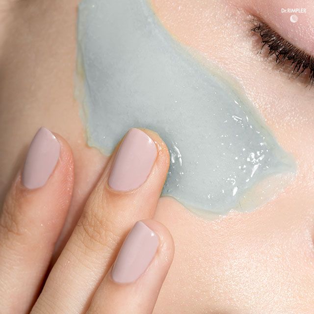Fingerspitzen tragen hellblaues Gel auf die Haut auf.