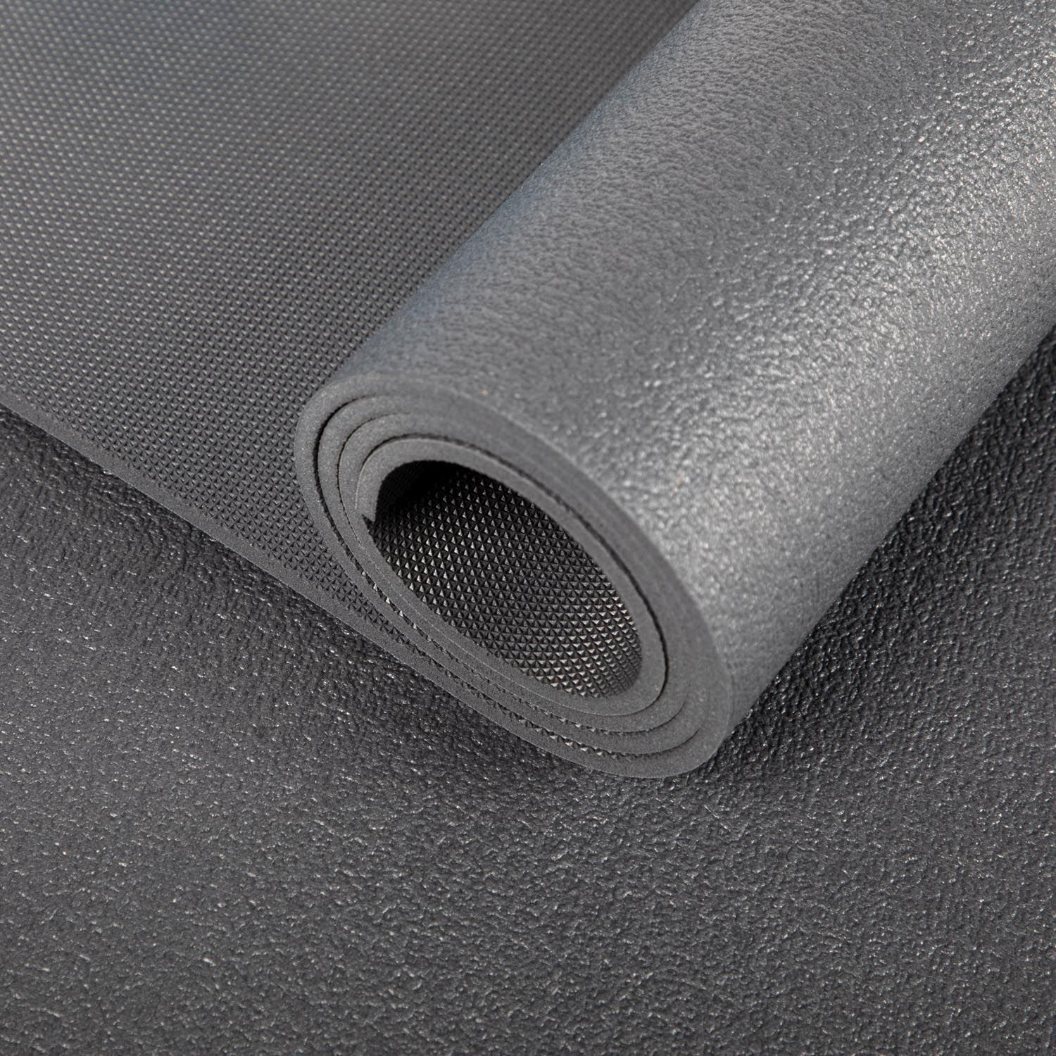 Gerollte Yogamatte, graue Farbe. Detailansicht der Oberfläche und des gerollten Endes.