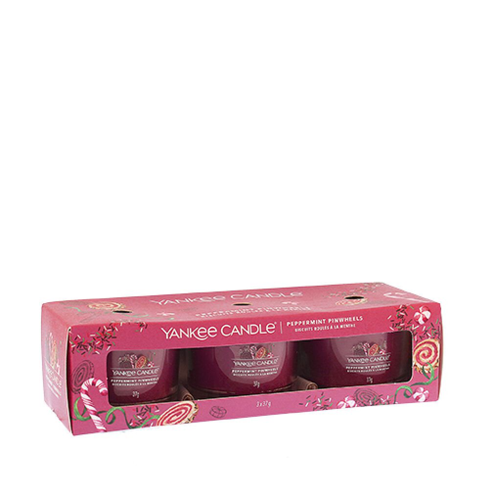 Set aus drei Votivkerzen in Glasbehältern. Verpackung mit Markenlogo und Produktbezeichnung. Rosa Verpackung mit weihnachtlichem Design.