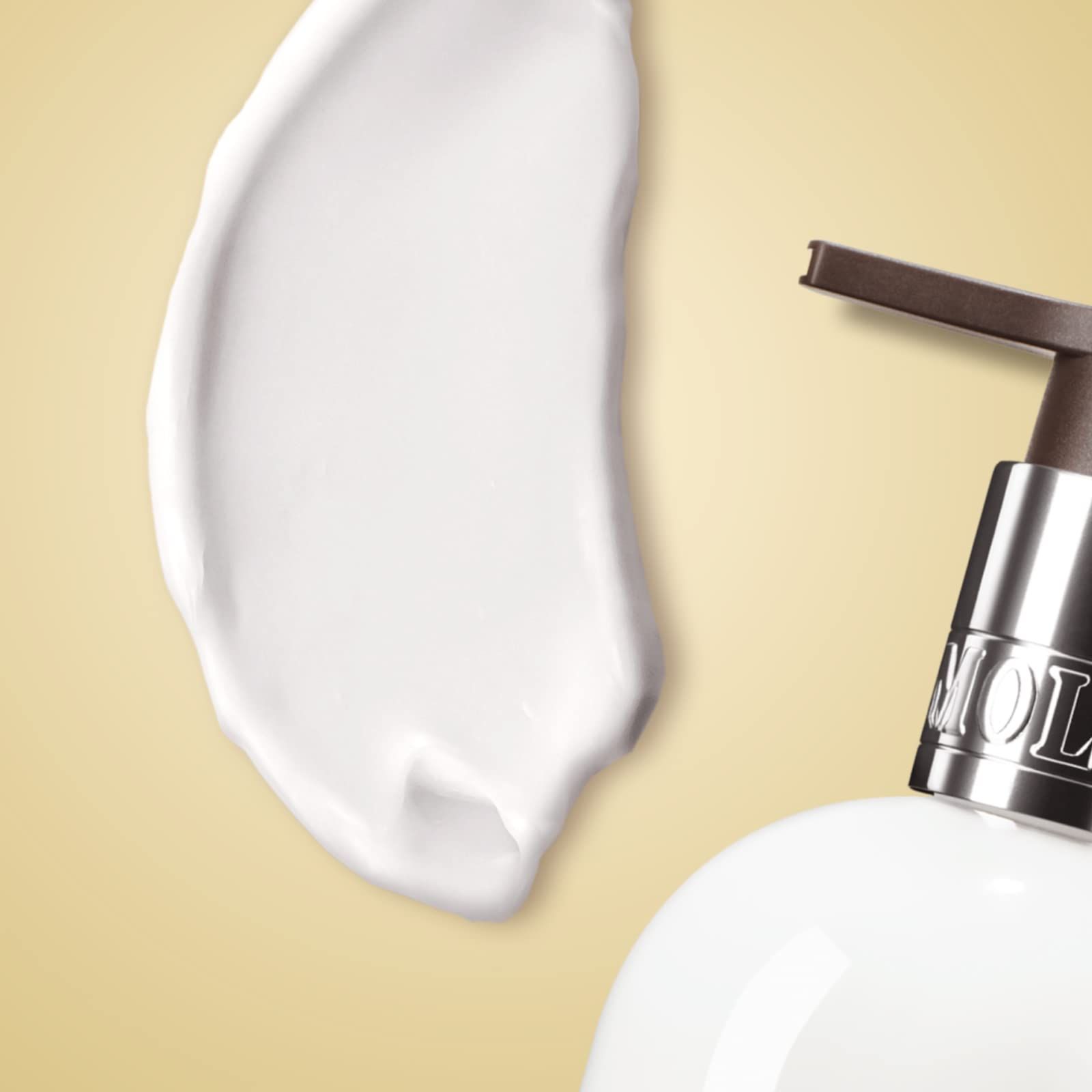 Weißer Klecks Körperlotion neben einer Flasche. Aufschrift: Molton Brown.