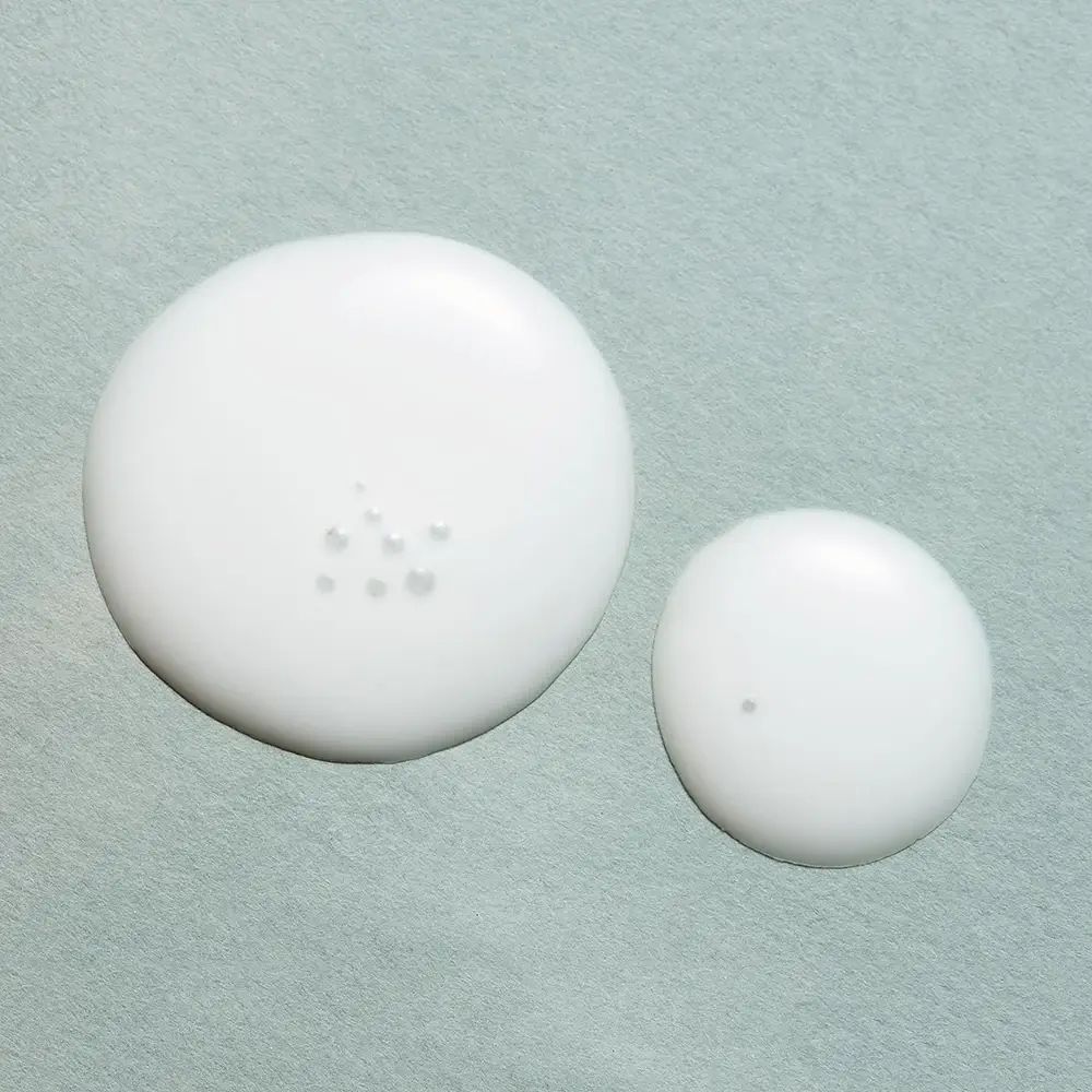 Zwei weiße Tropfen auf hellblauem Hintergrund. Kleinerer Tropfen mit einem einzelnen Punkt, größerer Tropfen mit mehreren Punkten.