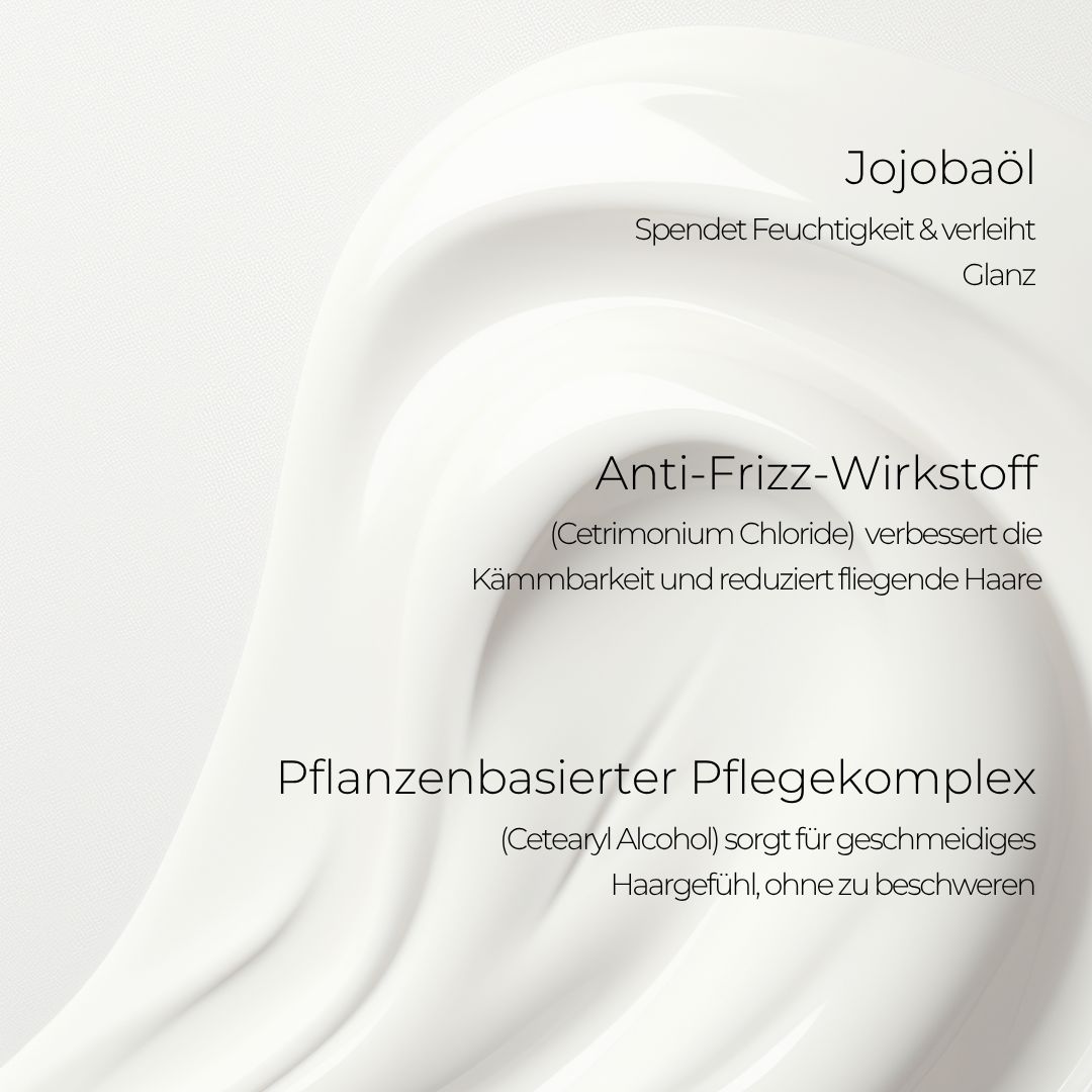 Nahaufnahme von cremiger Substanz. Text: Jojobaöl, Anti-Frizz-Wirkstoff, pflanzenbasierter Pflegekomplex.