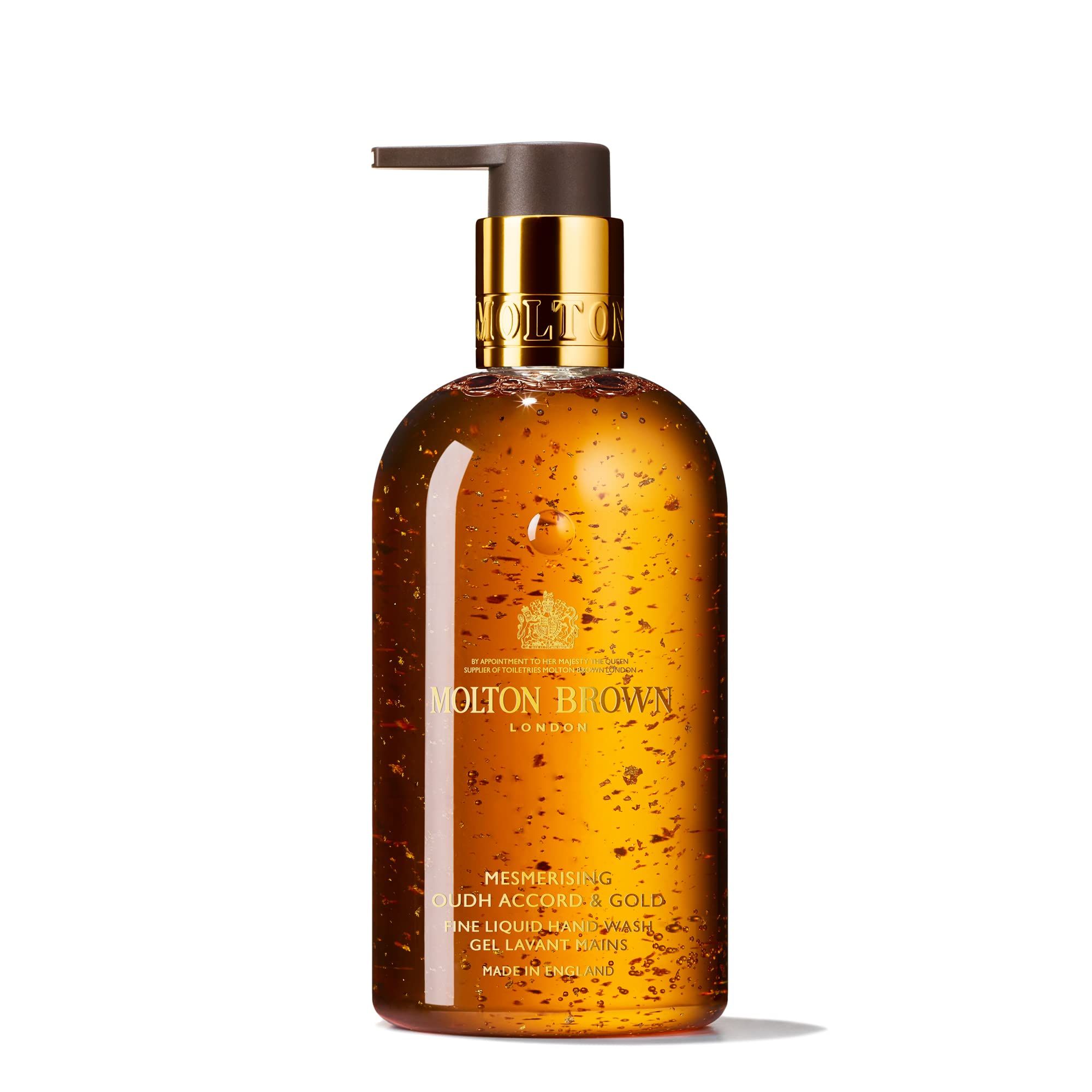 Molton Brown Handseife. Goldfarbene Flüssigkeit in einer Flasche mit goldfarbenem Pumpkopf. Text: Mesmerising Oudh Accord & Gold.