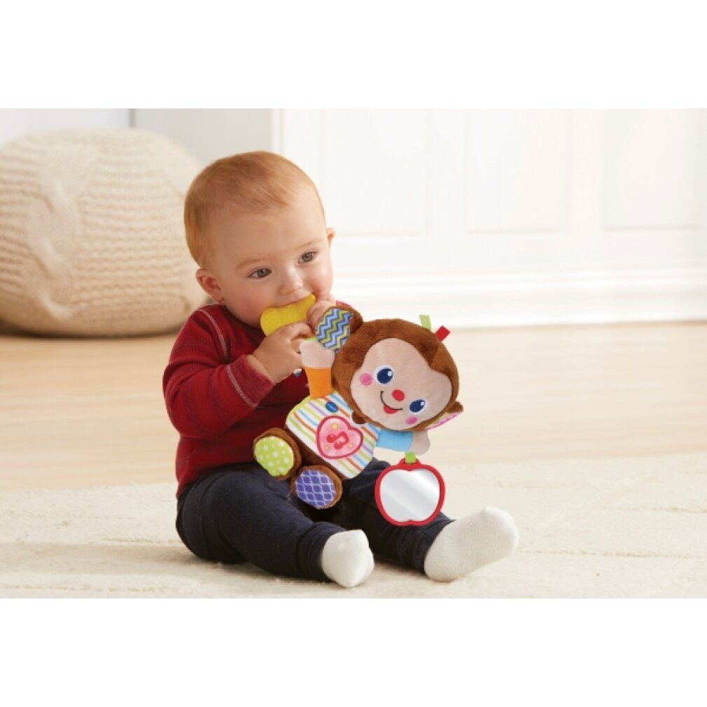 Baby beißt auf gelben Beißring des Plüsch-Äffchens. Äffchen mit Spiegel und bunten Details.