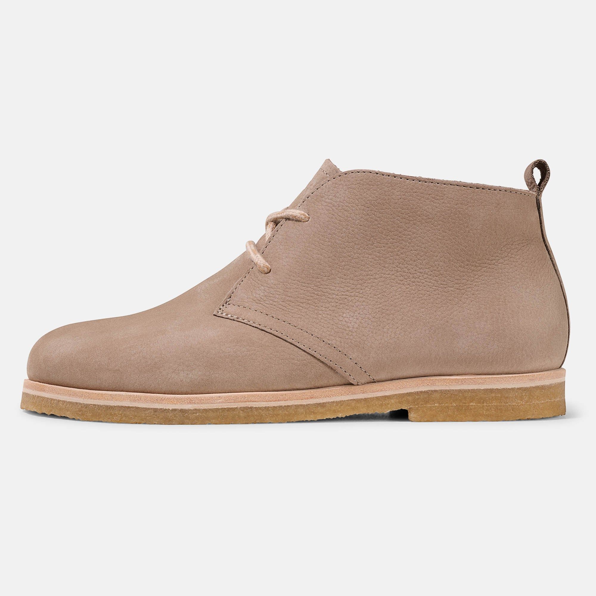 Hellbraune Stiefelette mit Schnürsenkeln. Flache Sohle, breite Passform. Schuh von der Seite, leicht erhöht.