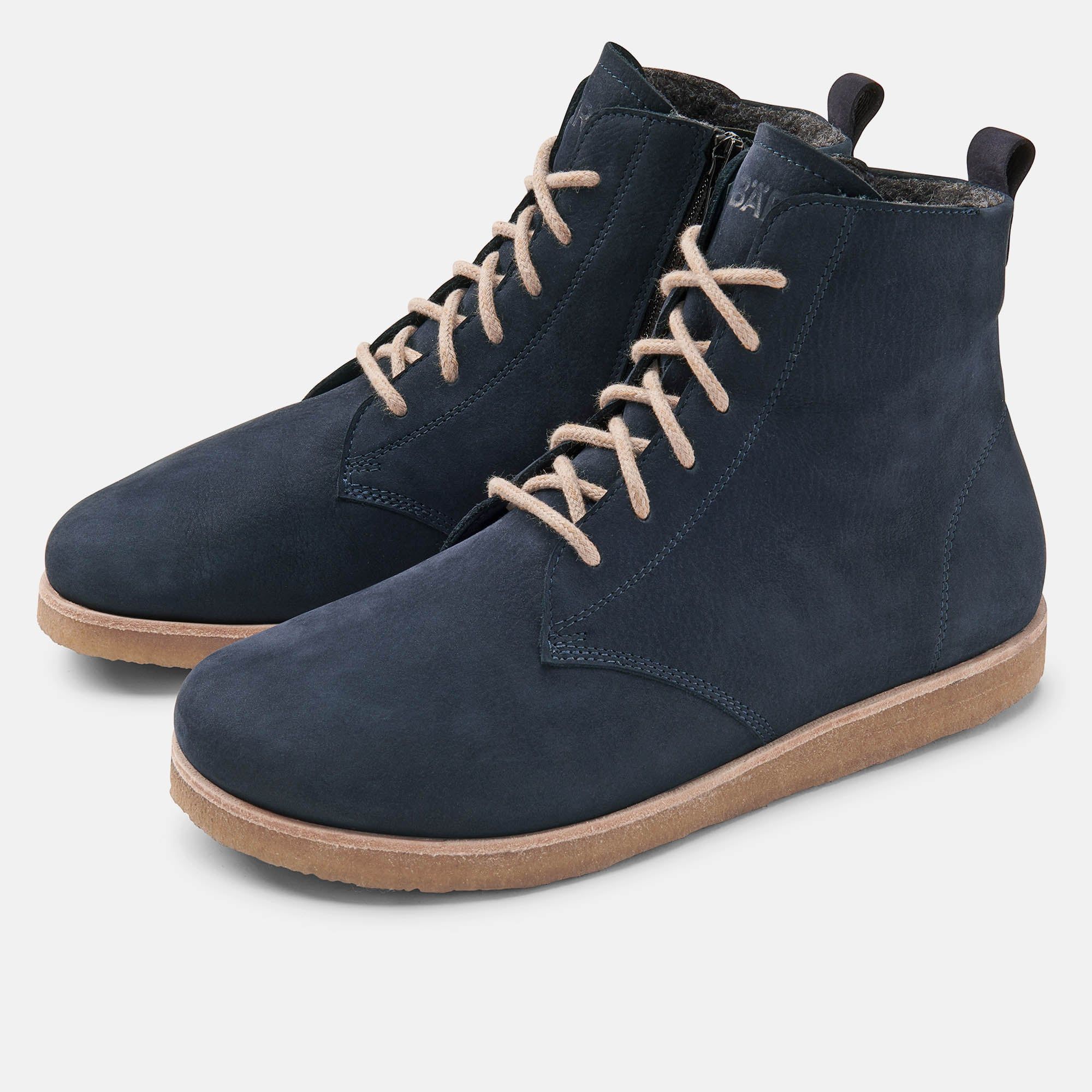 Blaue Stiefeletten mit Schnürsenkeln und Reißverschluss. Beige Schnürsenkel und Sohle. Hellgrauer Hintergrund.