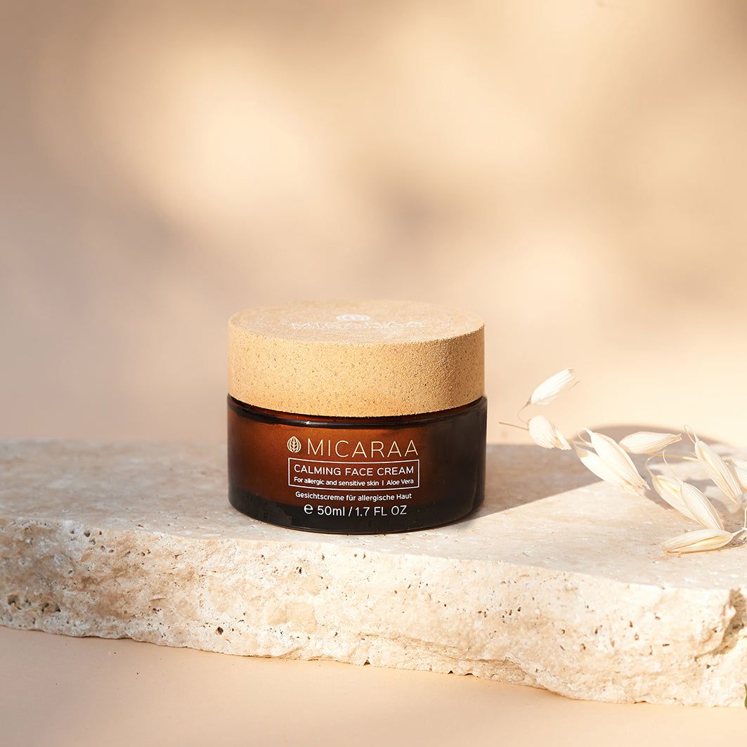 Braune Creme-Dose mit Holzdeckel auf einem Stein. Aufschrift: MICARAA Calming Face Cream. Für allergische Haut. Mit Aloe Vera. 50ml.