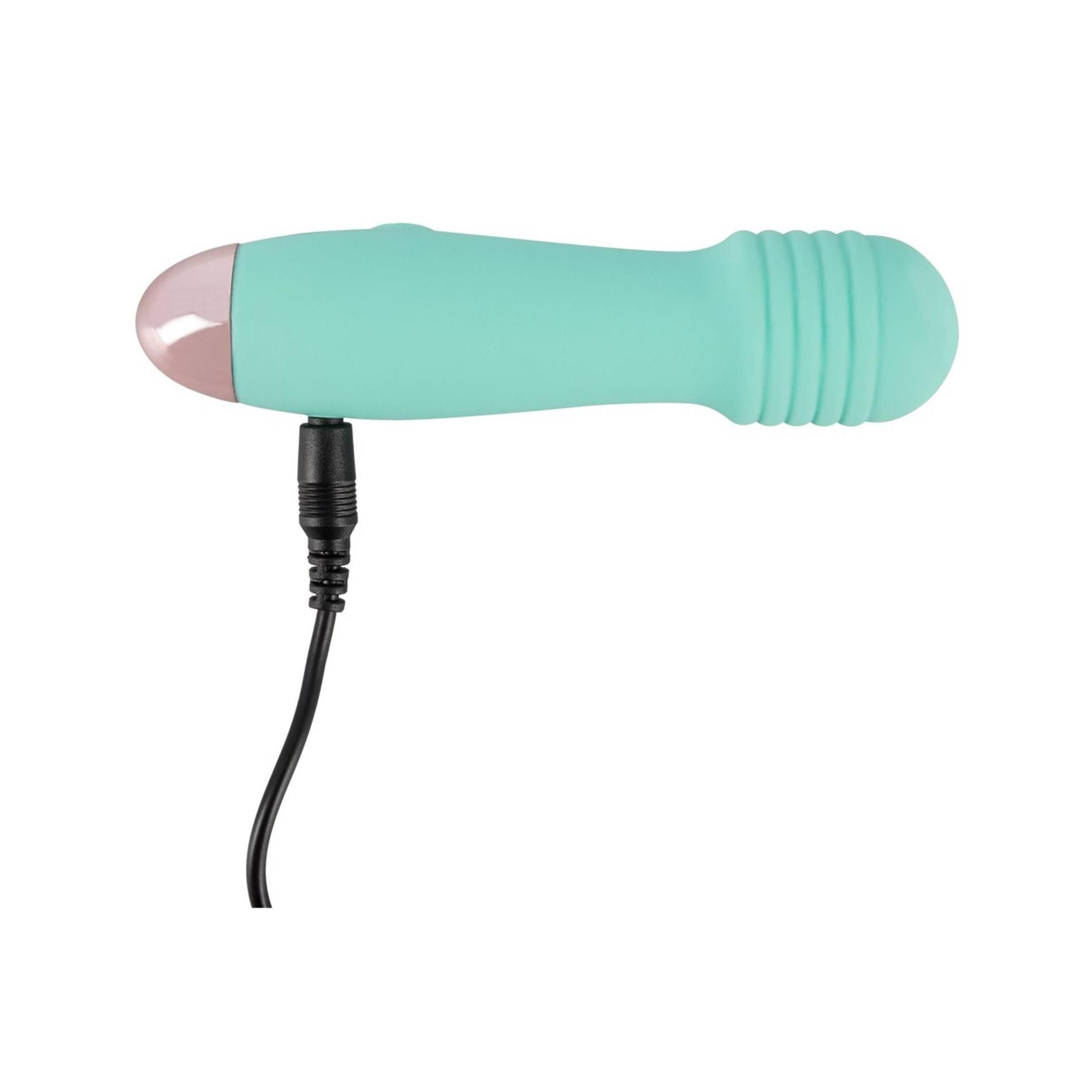 Minivibrator, mintgrün mit rosa Spitze, mit angeschlossenem Ladekabel. Der obere Teil hat Rillen. Ein Knopf ist sichtbar.