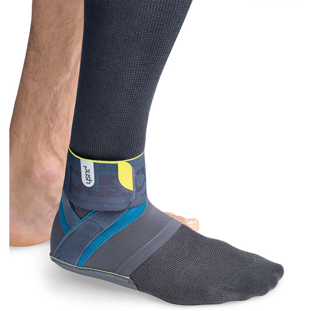 Knöchelbandage am Bein getragen. Grau-blau mit gelben Akzenten. Das Wort "push" ist sichtbar.