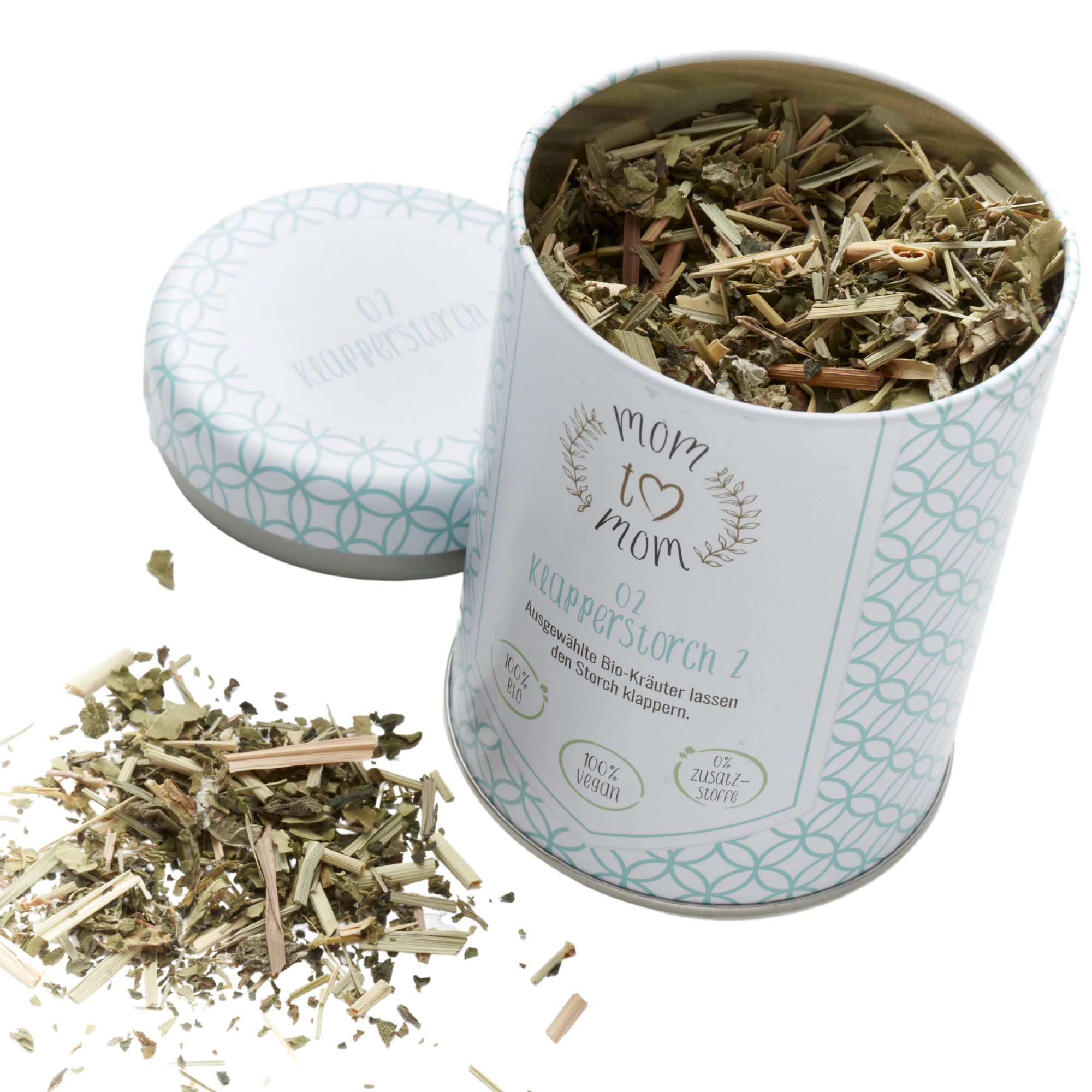Geöffnete Dose mit Kräutermischung. Aufschrift: mom to mom, Klapperstorch 7. Dose mit Deckel, Kräuter liegen daneben.