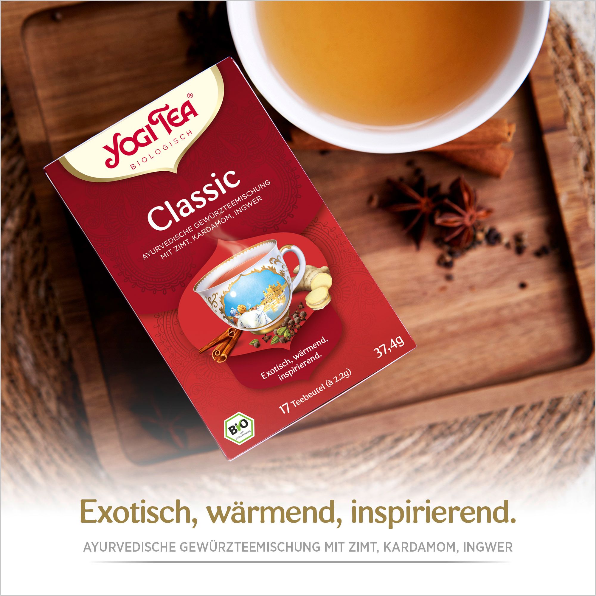 Yogi Tea Classic Packung auf Holzbrett. Tasse Tee daneben. Logo, Produktname und Zutaten auf der Packung. Bio-Siegel. 17 Teebeutel.