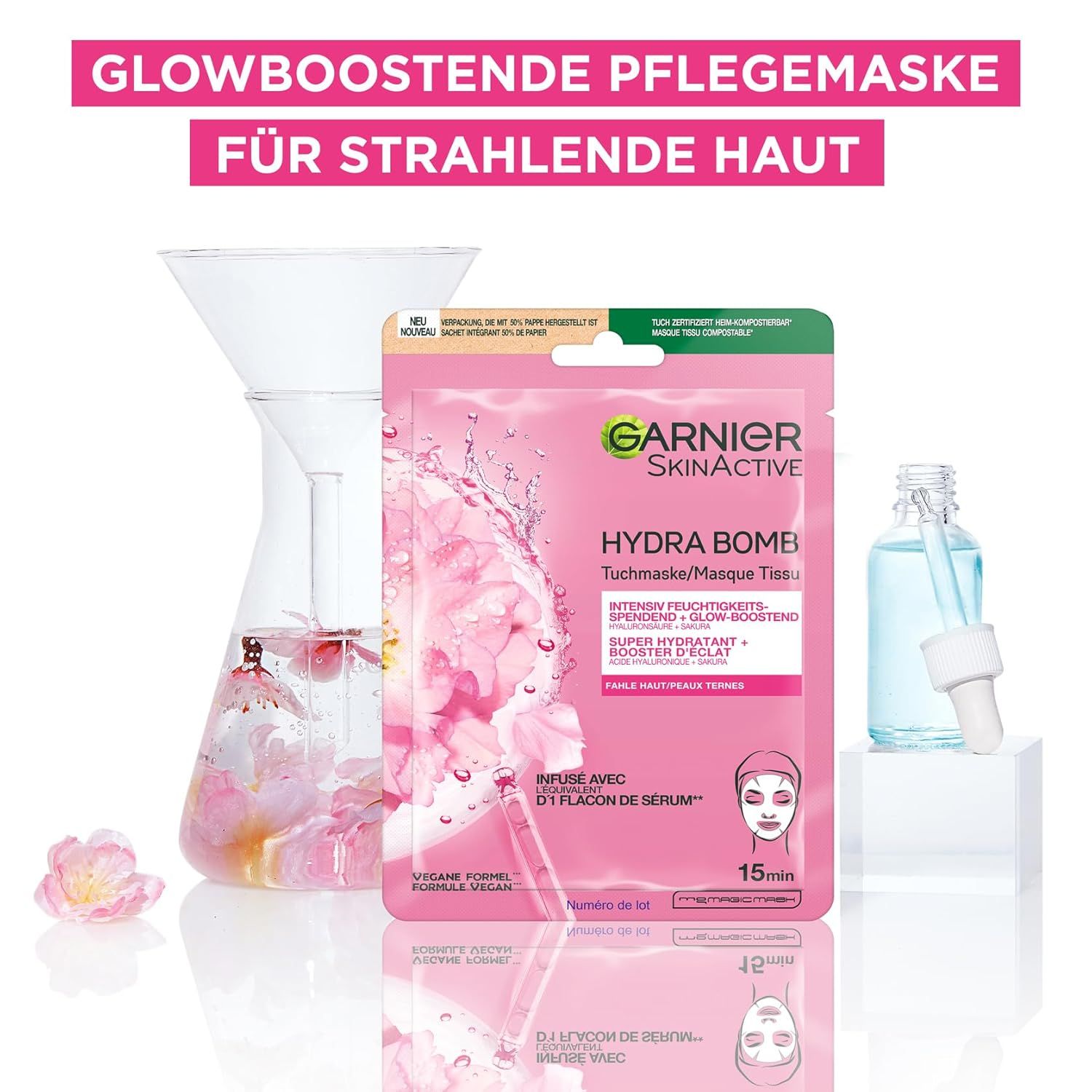 Garnier SkinActive Hydra Bomb Tuchmaske, neben Laborutensilien und Serumflasche. Text: Glowboostende Pflegemaske für strahlende Haut.